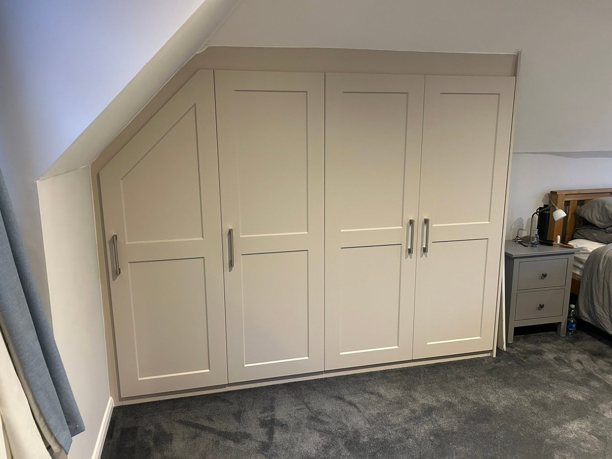 Cream fitted wardrobe shaped around a sloped bedroom ceiling