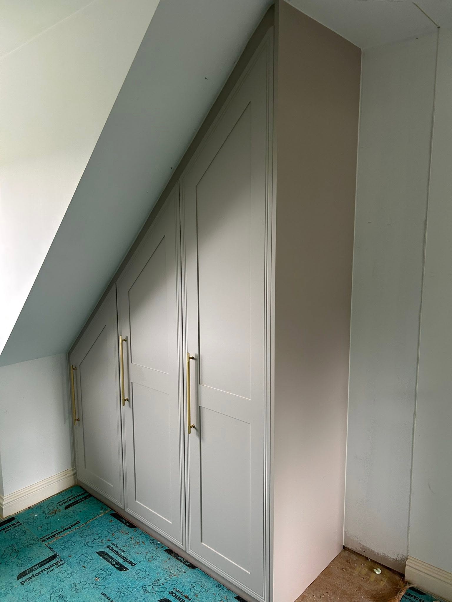 White shaker wardrobes built under a sloped ceiling