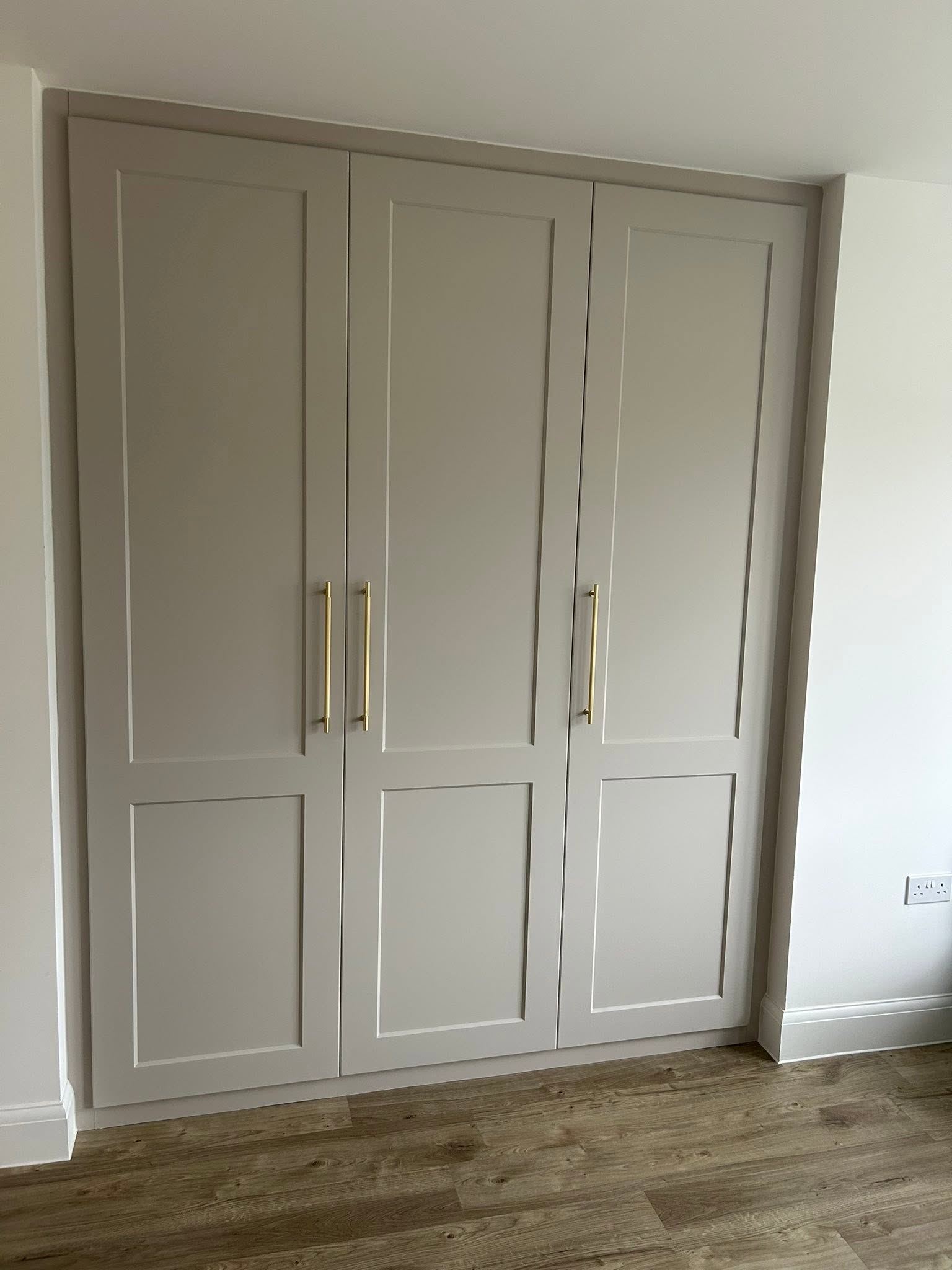 Three-door cream shaker wardrobe with brass handles